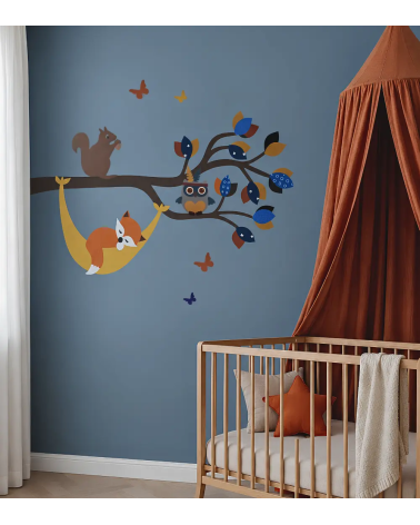 Muurdecoratie van een bosdierentak met een vosje in een hangmat in een donkerblauwe en terracotta babykamer.