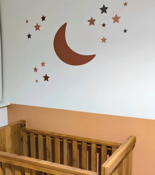 Roest kleurige boho maan muurdecoratie met sterren in terracotta babykamer.