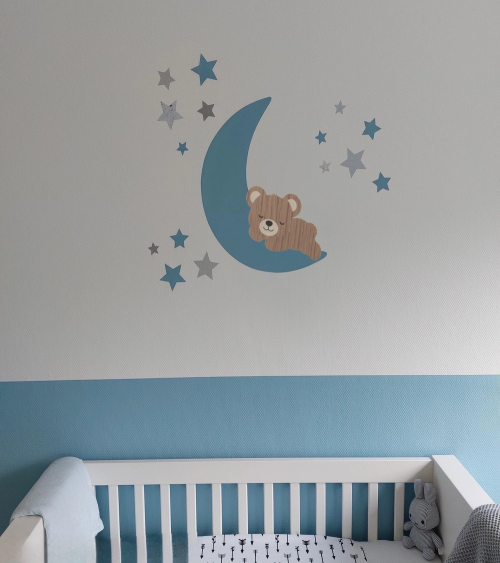 Muursticker babykamer slapende teddybeer op een lichtblauwe maan met sterren.