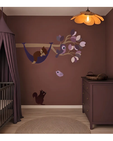 Mauve kleurige babykamer met een paarse bosdieren tak als wanddecoratie met een slapend vosje in een hangmat.