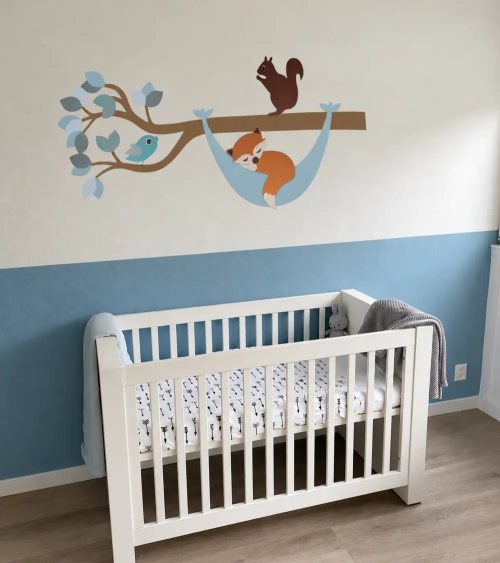 Bosdieren tak muurdecoratie met een slapend vosje in een hangmat in een lichtblauwe jongens babykamer.